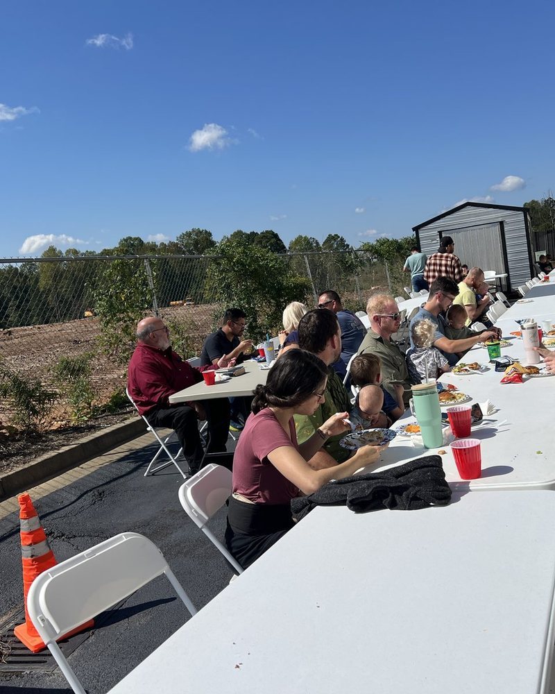 Church families sharing a meal at long tables outside the church building
