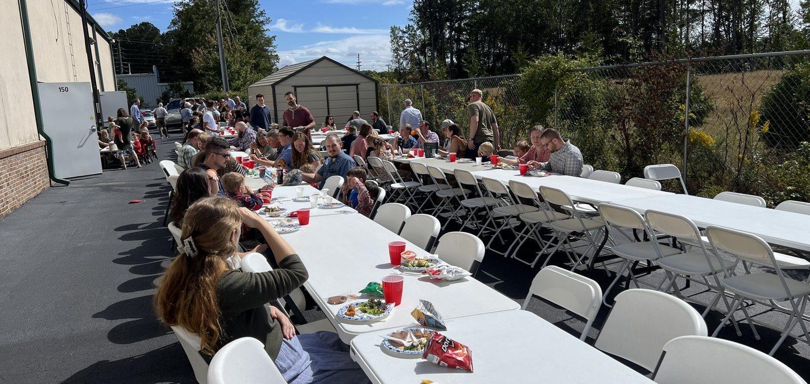 Church families eating together at long tables outside the church
